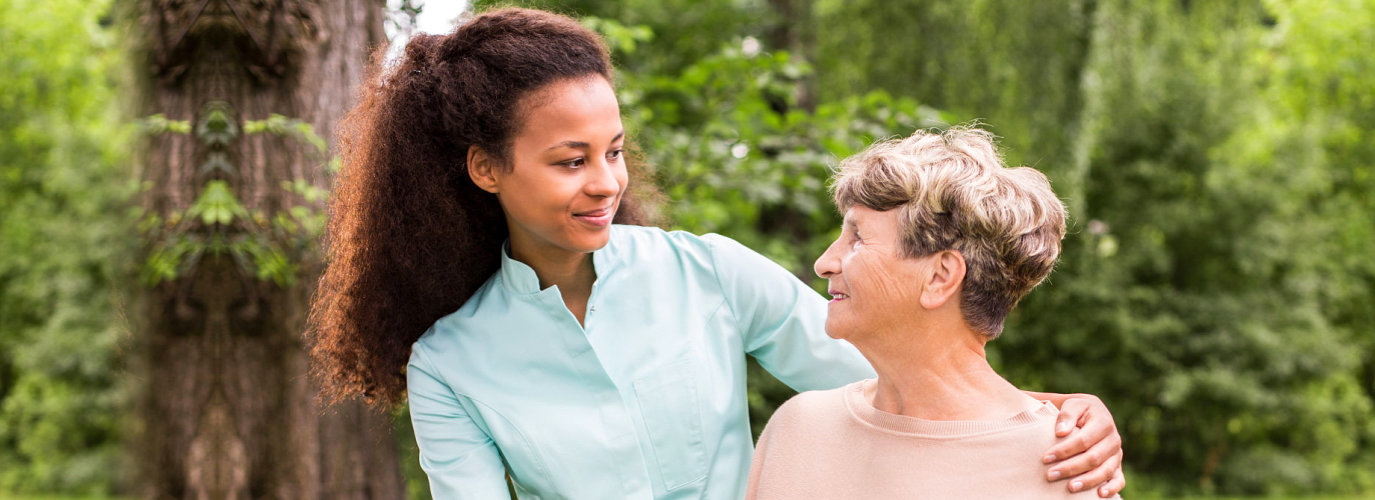 female caregiver and senior woman smiling outdoor