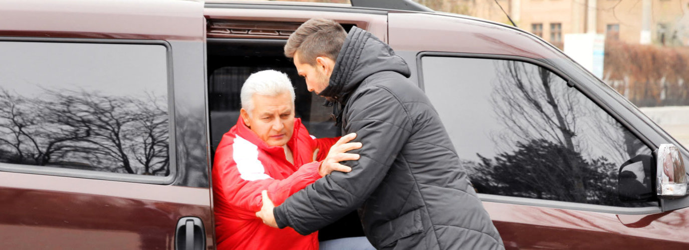 caregiver assisting senior man to stand